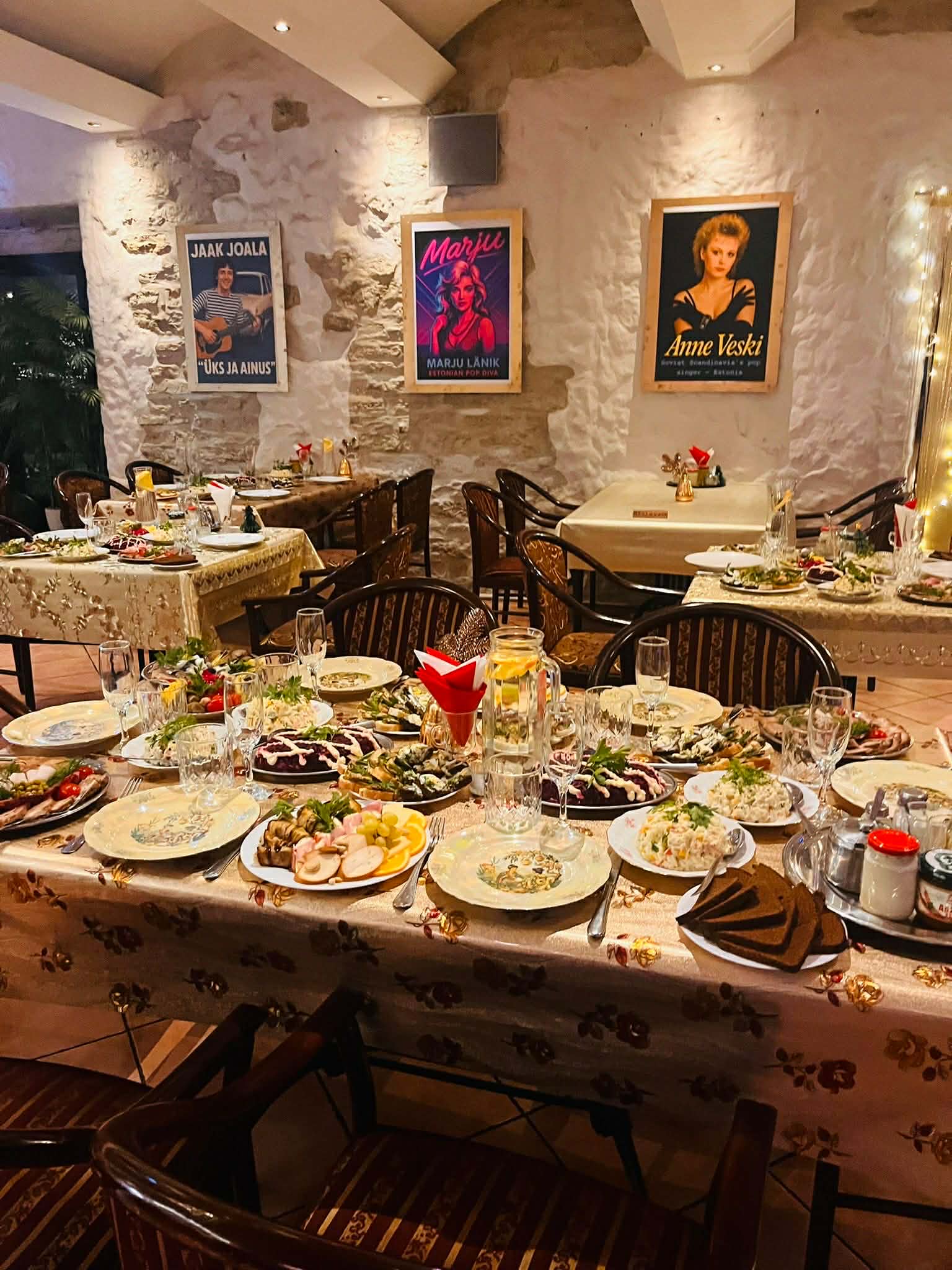 The interior of a cozy restaurant is decorated with numerous framed photographs and posters on the walls, creating a nostalgic atmosphere. Wooden tables and chairs are arranged neatly throughout the room, with patrons sitting and enjoying their meals. The lighting is soft, complementing the vibrant blue walls.